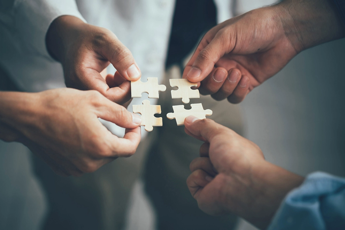 Building Business Success Through Strategic Partnerships Hands connecting puzzle pieces to symbolize business partnerships, collaboration, and strategic growth.